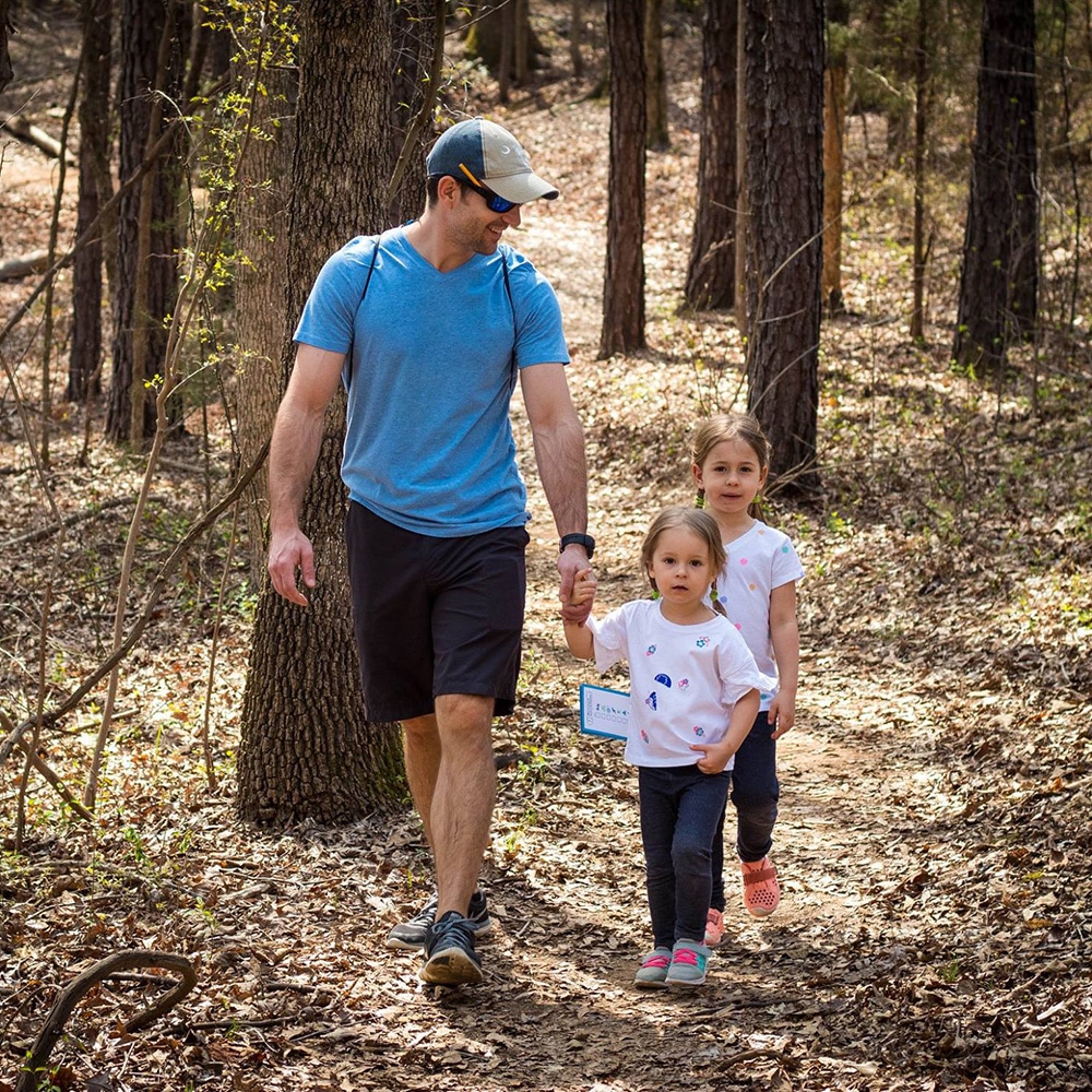 Photo of father walking the trails of the Anne Springs Close Greenway with 2 daughters while holding young daughter's hand